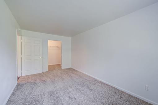 a bedroom with a carpeted floor and a door to a closet at Carolina Springs Apartments, Carrboro, NC  
