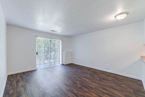 an empty living room with wood flooring and a sliding glass door at Carolina Springs Apartments, Carrboro, North Carolina  