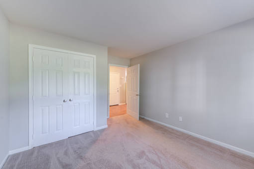 a bedroom with a white door and a large empty room at Carolina Springs Apartments, North Carolina  