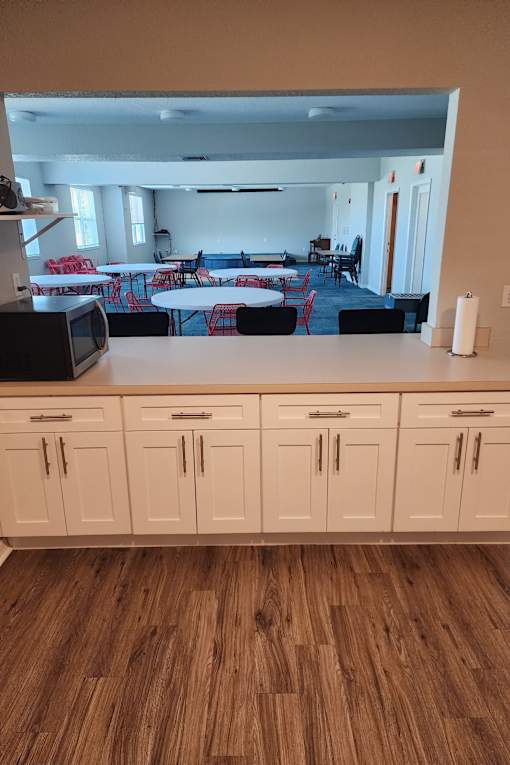 A kitchen with wooden floors and white cabinets.
