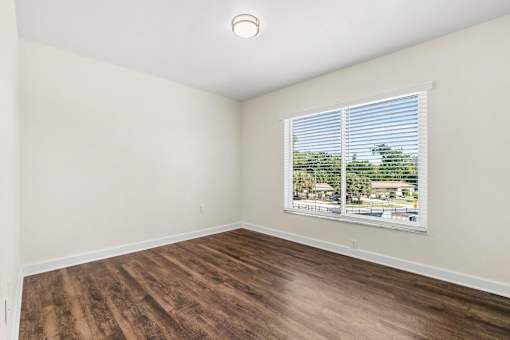 A room with a window showing a view of a residential area.