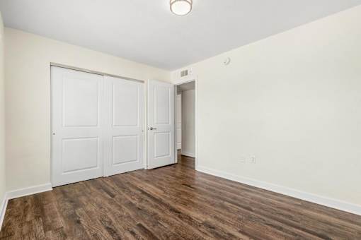 A room with a white door and a brown floor.