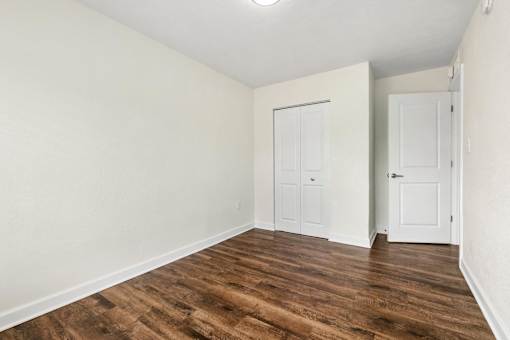 A room with wood flooring and two white doors.