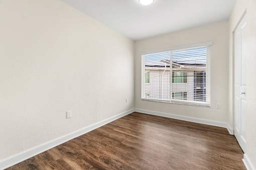 A room with wooden flooring and a window with blinds.