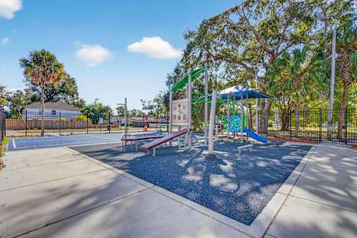 A playground with a blue umbrella and a basketball court.