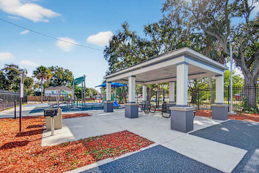 A bus stop shelter is located in a park with a bench and a bike rack.