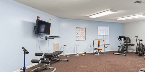 a fitness center with exercise equipment and a tv on the wall