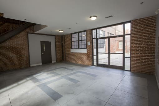 an empty room with a large glass door and a brick wall
