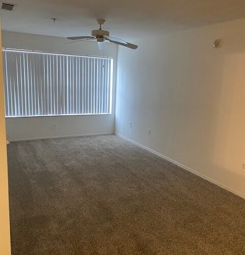 an empty room with a ceiling fan and a window