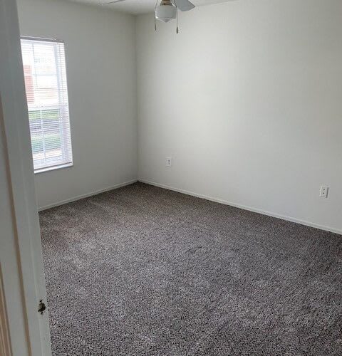 an empty room with a carpet floor and a window