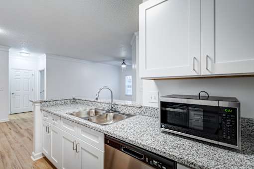 A kitchen with white cabinets and a granite countertop.