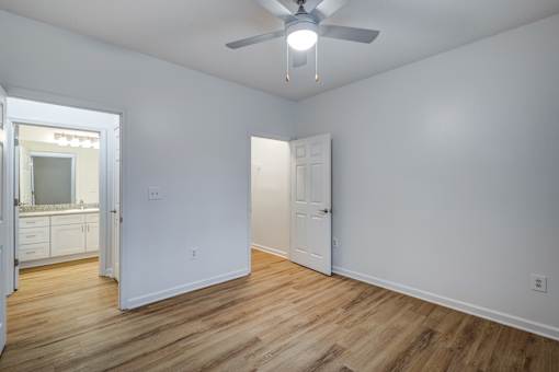A room with a ceiling fan and wooden flooring.