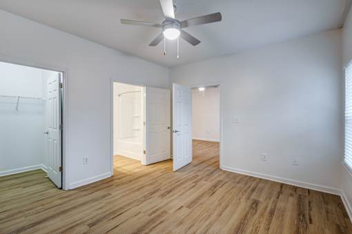 A room with a ceiling fan and wooden floors.