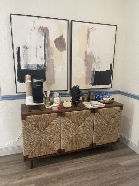 two paintings hanging on a wall next to a wooden shelf