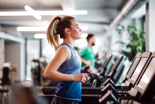 a woman running on a treadmill at a gym
