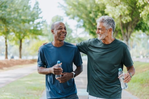 two men walking in the park holding bottles of water