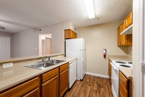 A kitchen with wooden cabinets and a white refrigerator at Lakeside Gardens Apartments, North Carolina