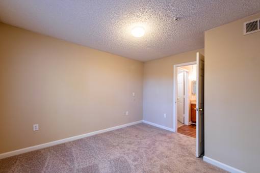 A room with a carpeted floor and a doorway leading to another room at Lakeside Gardens Apartments, Durham, NC