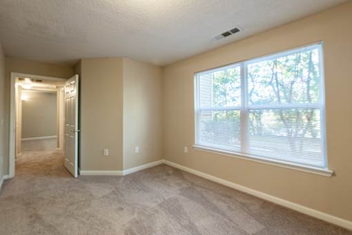A room with a carpeted floor and a window with blinds at Lakeside Gardens Apartments, Durham, North Carolina