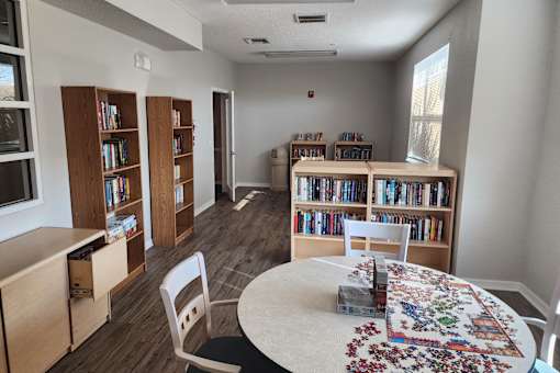 A room with a table, chairs, and bookshelves.