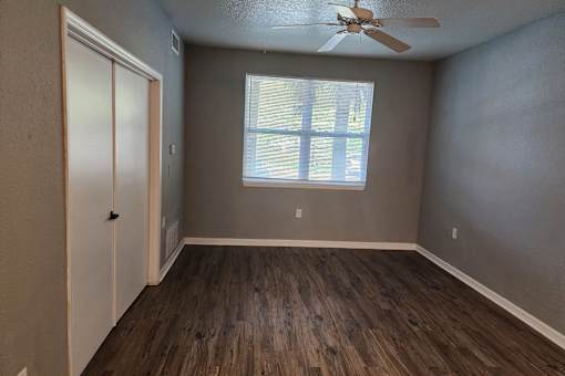 A room with a ceiling fan and a window with blinds.