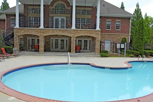 a swimming pool in front of a house with a resort style pool