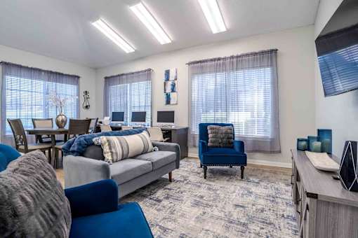 A living room with a grey couch, blue chairs, and a rug.