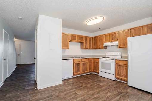 A kitchen with white appliances and wooden cabinets.