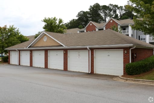 a garage with white doors in front of a house at Magnolia Lake Apartments, Carrollton, Georgia
