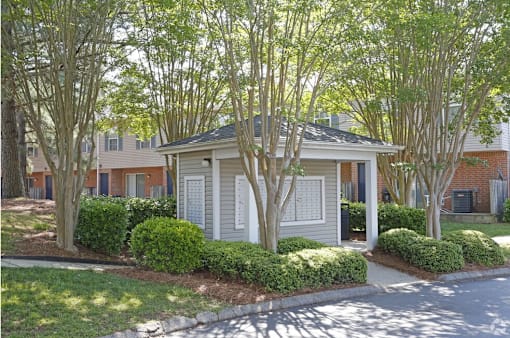 A house with a white door and windows is surrounded by trees.