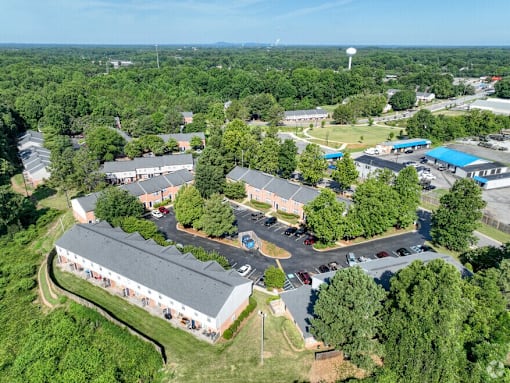 A bird's eye view of a school with a parking lot and a water tower in the distance.