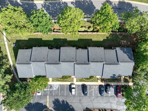 A parking lot with cars and a building with grey roofs.