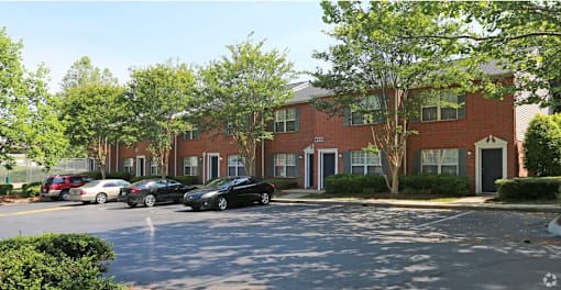 A black car is parked in front of a brick building.