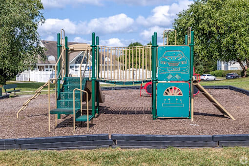 A playground with a green slide and a red and green play structure.