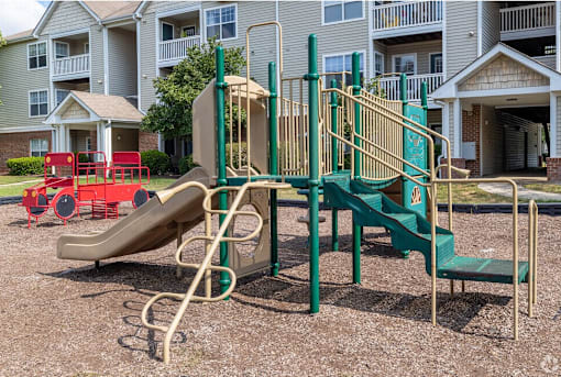 A playground with a green slide and a red slide.