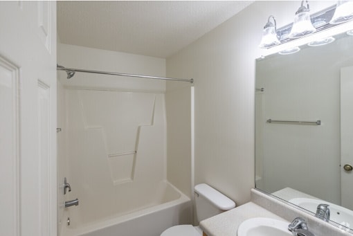 A white bathroom with a toilet, sink, and bathtub.