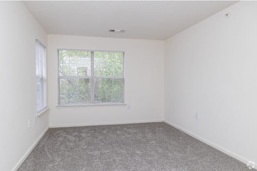 A room with a window and a carpeted floor.