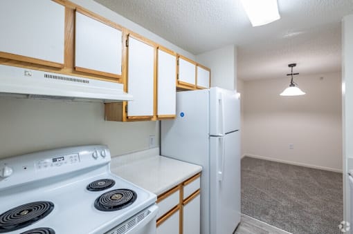 A kitchen with a white stove top oven and a white refrigerator.