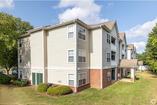 A large apartment building with a green lawn in front.