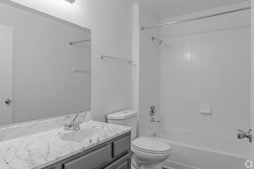 A white bathroom with a marble countertop and a toilet.