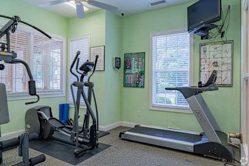 A home gym with a treadmill, elliptical trainer, and stationary bike.