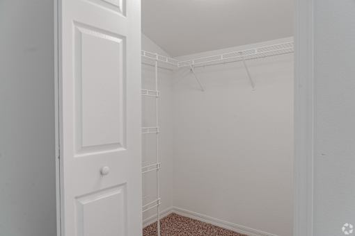A white door is open to a room with a white wall and a white floor.