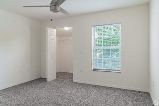 A room with a ceiling fan and a window with blinds.