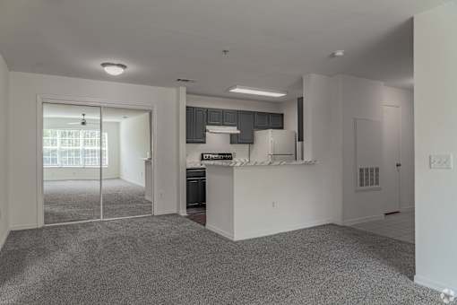 A kitchen area with a refrigerator, cabinets, and a window.