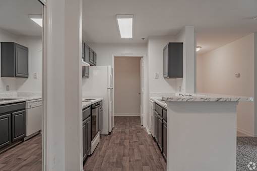 A kitchen with white appliances and dark wood floors.