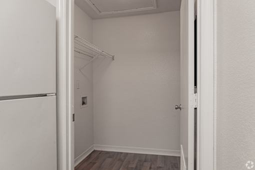 A white closet with a white door and a white wall.