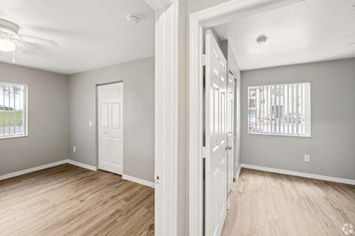 A room with a white door and a window with white blinds.