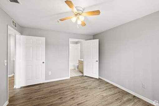 A room with a ceiling fan and wooden floors.