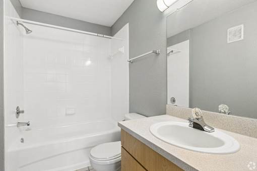 A white bathroom with a toilet, sink, and shower.