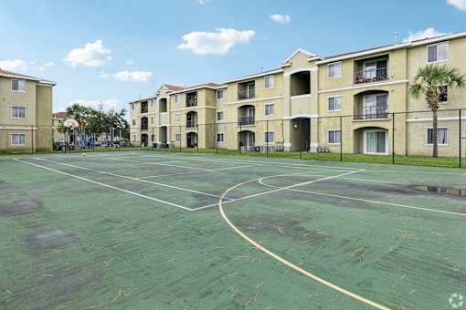 A basketball court in front of apartment buildings.